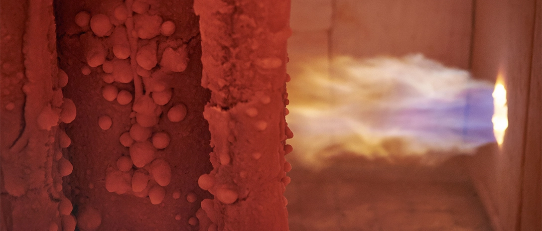 A bright flame in a testing furnace illuminates an intumescent coating inside, part of passive fire protection research at the Santa Perpetua.