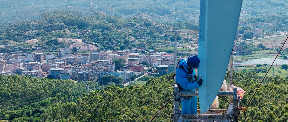 Technician performing rotor blade maintenance, applying protective coating to a wind turbine blade.