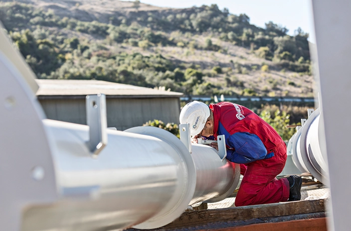 A coating advisor from Hempel inspecting the surface of a pipe in an outdoor environment.