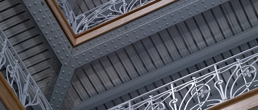 A close-up of decorated metal railings and beams in an architectural structure.