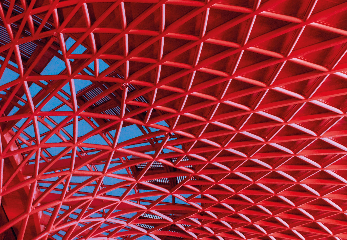 A close-up view of a red metal civil structure, set against a bright blue sky.