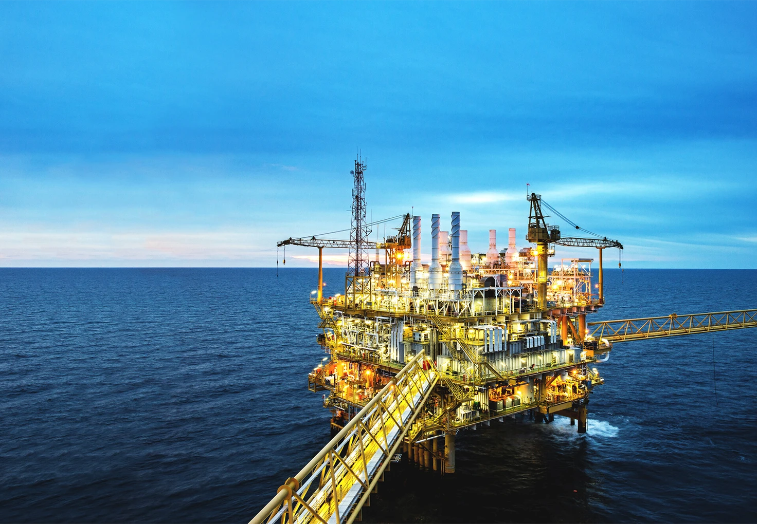 Offshore oil platform lightened up, surrounded by calm ocean waters under a blue sky