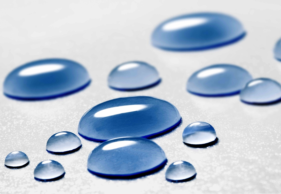 Close-up of water droplets on a smooth surface, showcasing hydrophobic properties.