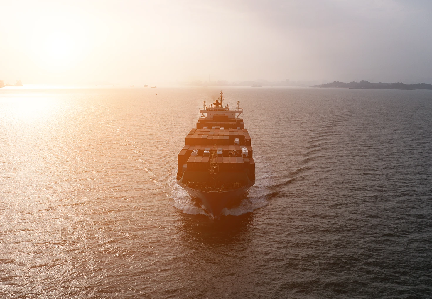 A cargo ship seen from above on the sea at sunset