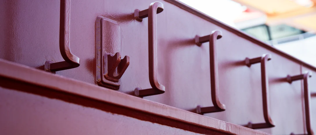 Close-up of red-coated ladder rungs welded to a ship's hull.