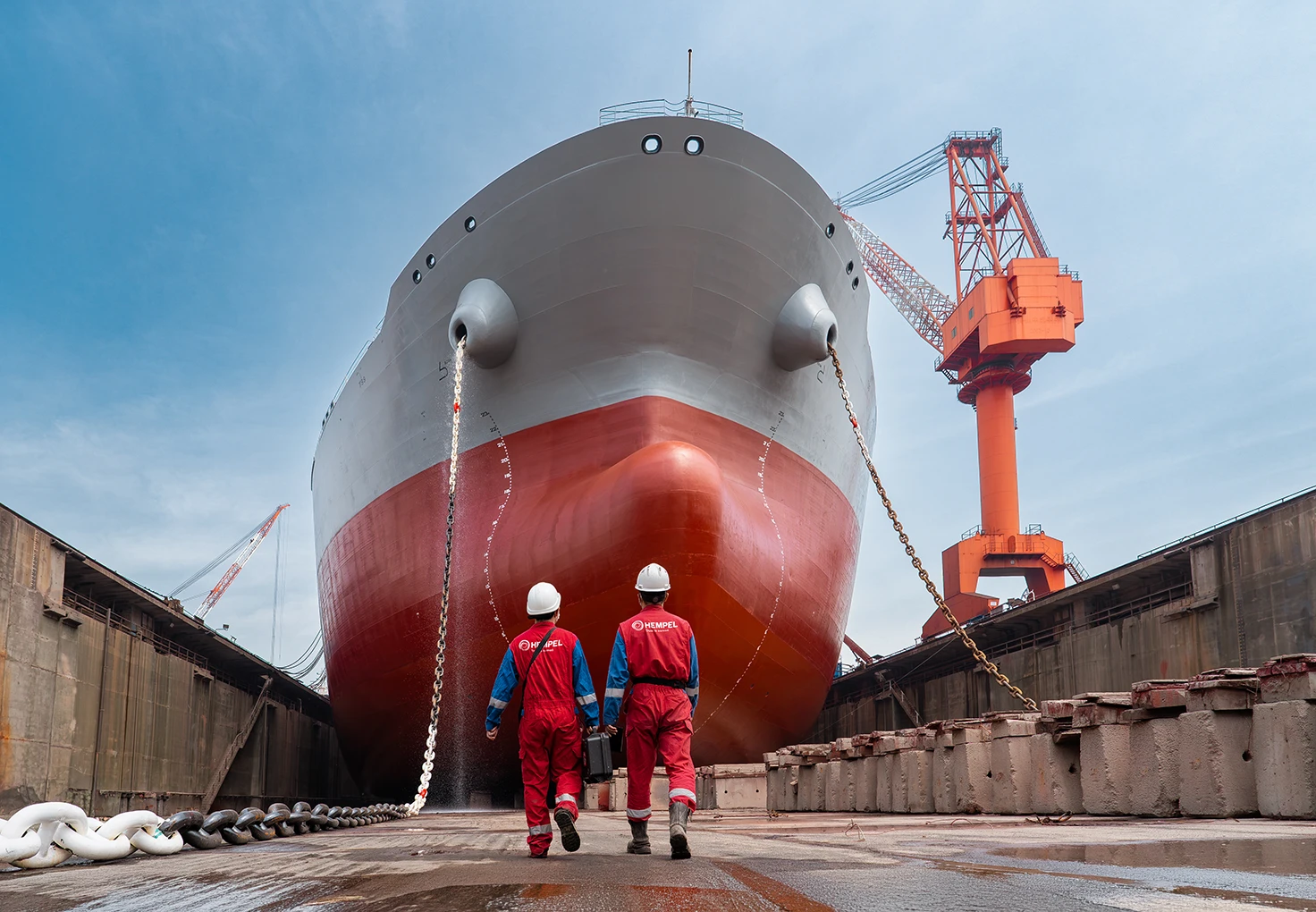 Large ship in dry dock with two coating system advisors inspecting the hull.
