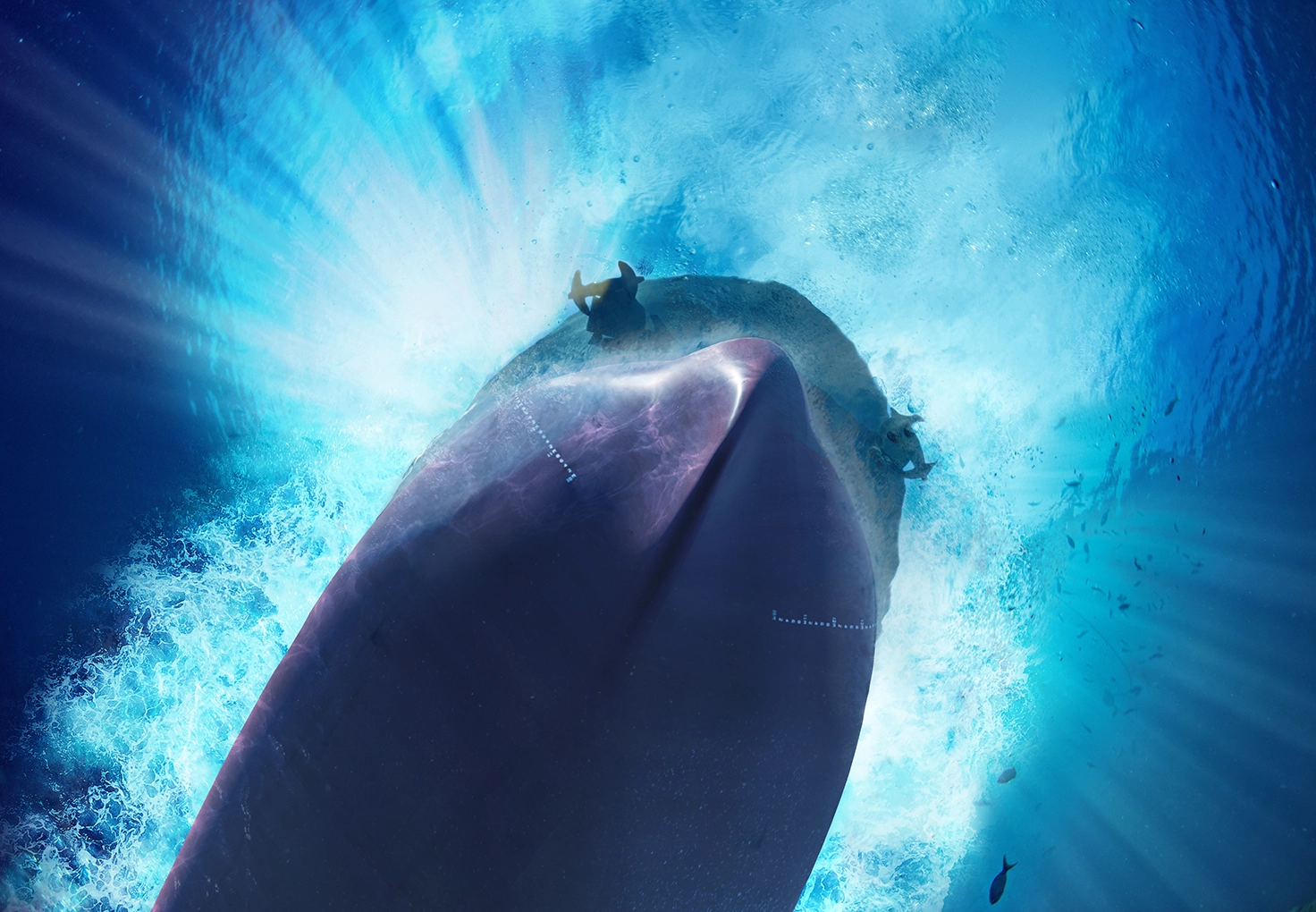 Underwater view of the front bow of a ship moving through the water, creating a radiant burst of light and bubbles around the hull.
