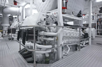 A view of the yacht's engine room, showing clean, white machinery and complex piping.