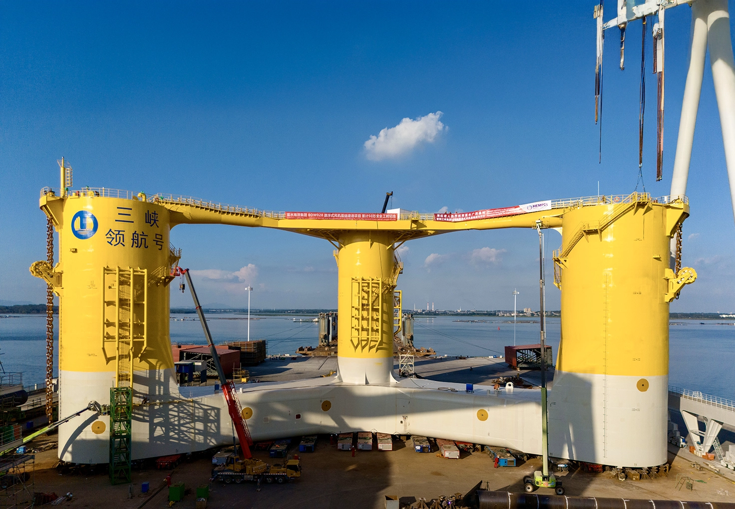 A large yellow floating wind turbine foundation is being lifted into the water at the Three Gorges Yangjiang project in China.