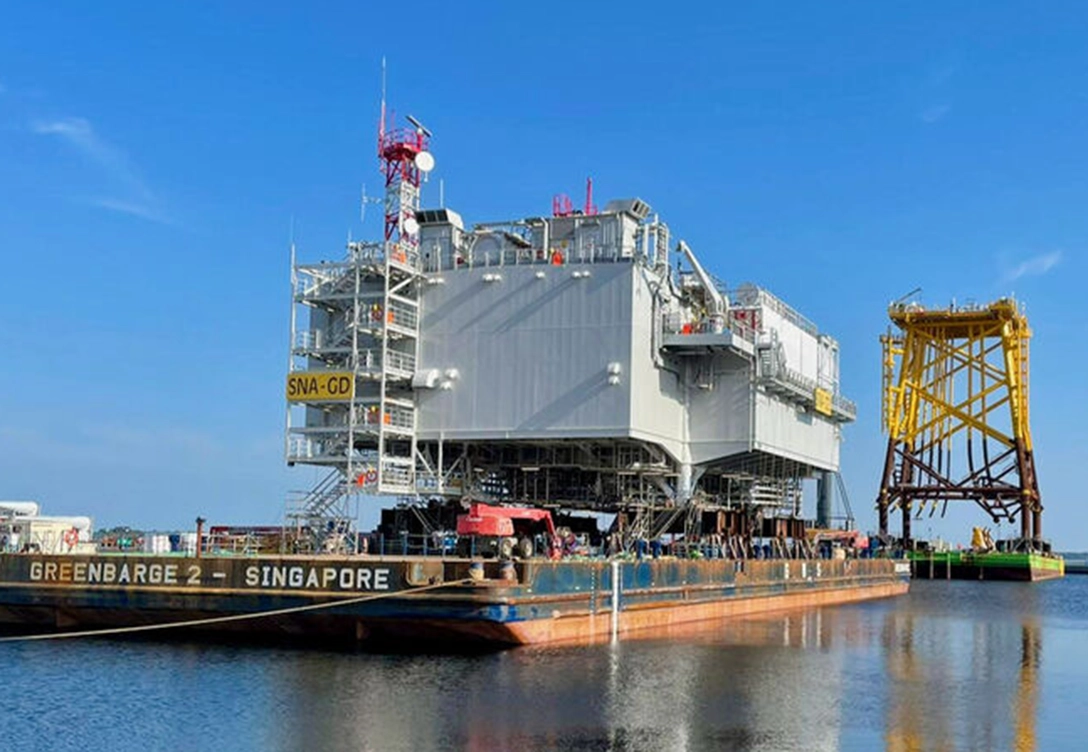 An offshore substation on a barge in the process of being transported at Chantiers de l’Atlantique shipyard.