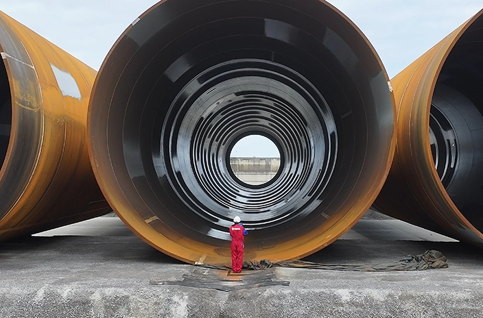 Offshore wind foundation monopiles with a Hempel coating advisor standing in front of them.
