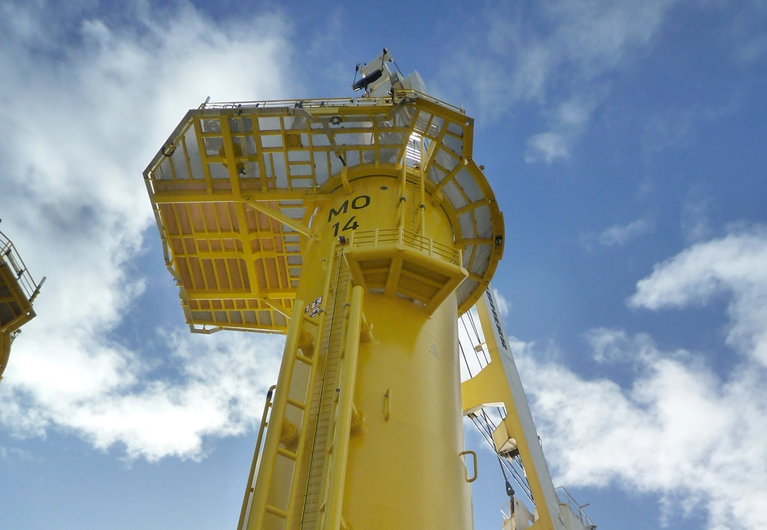 A close-up view of a towering yellow foundation structure for the Merkur Windfarm under clear skies.