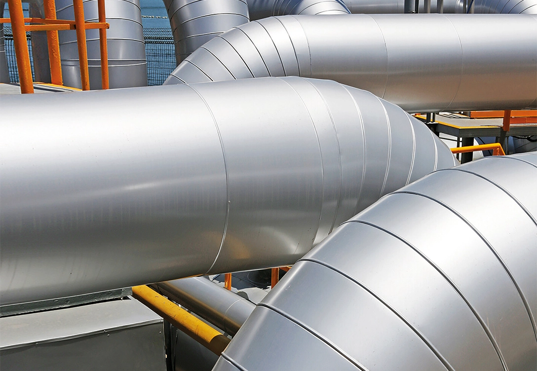 Close-up view of several large insulated metal pipes in an industrial setting.