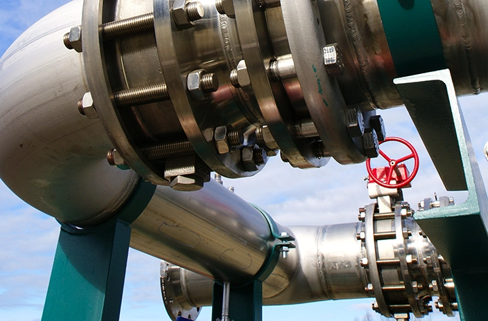 Close-up view of industrial pipes and a red valve.