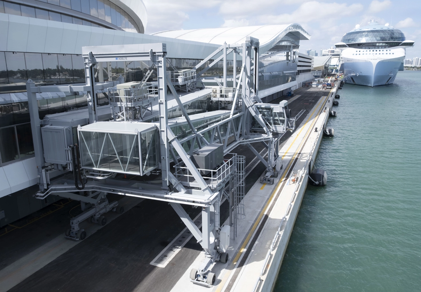 Passenger boarding bridge at a modern cruise terminal beside docked cruise ship.