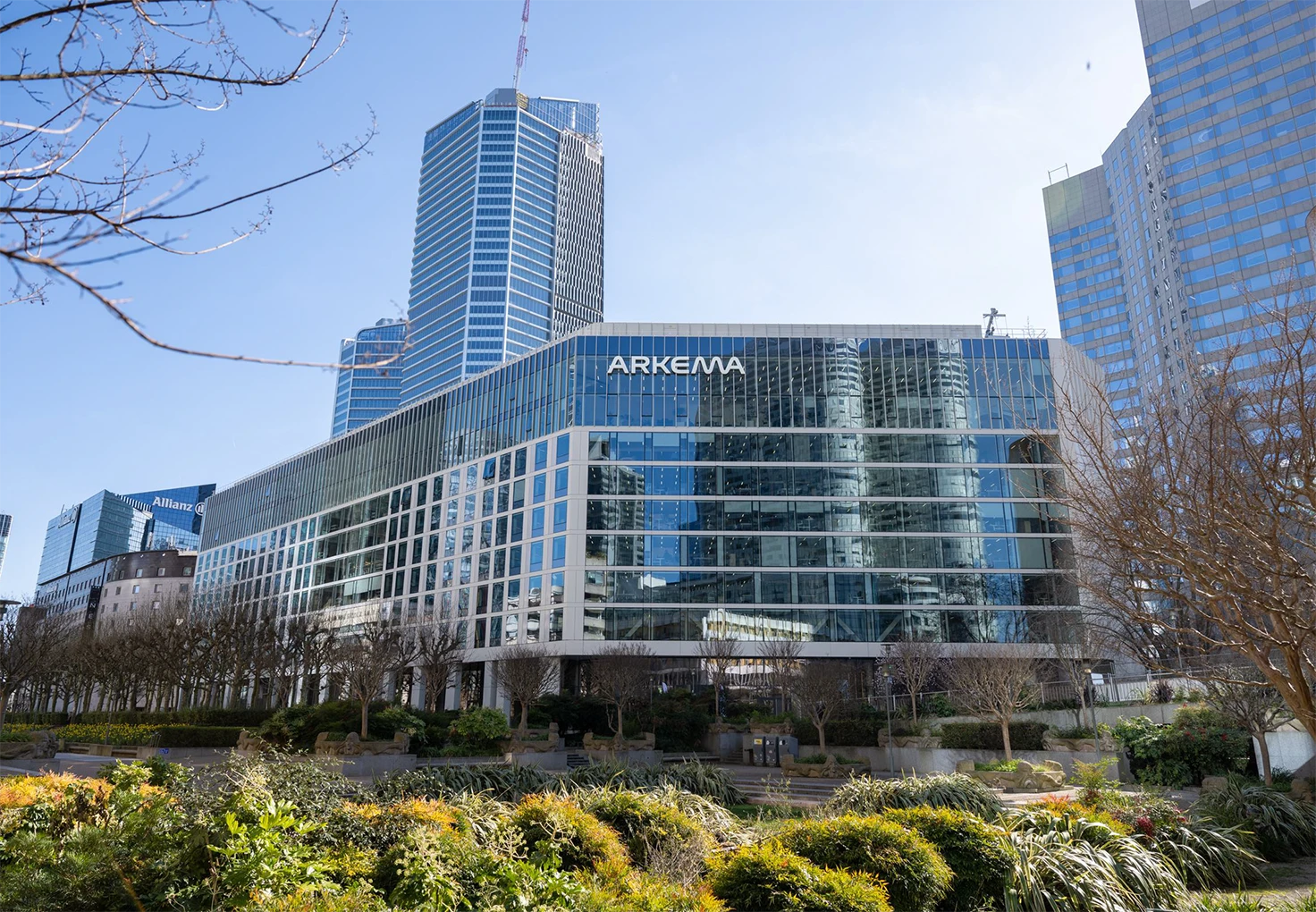 Arkema headquarters building with a modern glass facade and surrounding city skyline.