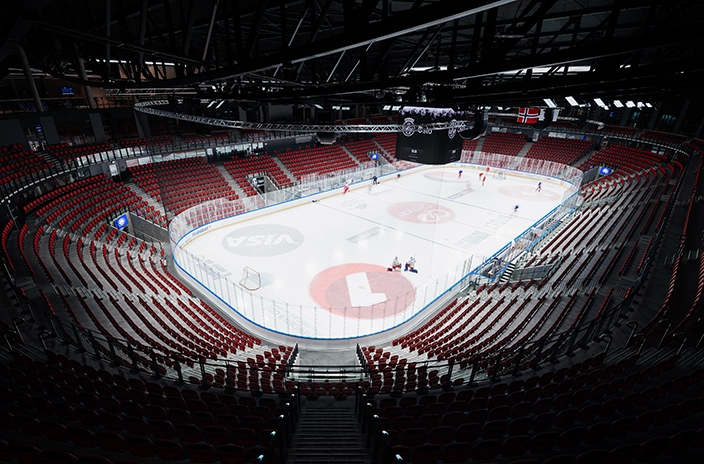Empty ice hockey arena at Jordal Amfi Stadium, with red seats and a rink ready for a game.