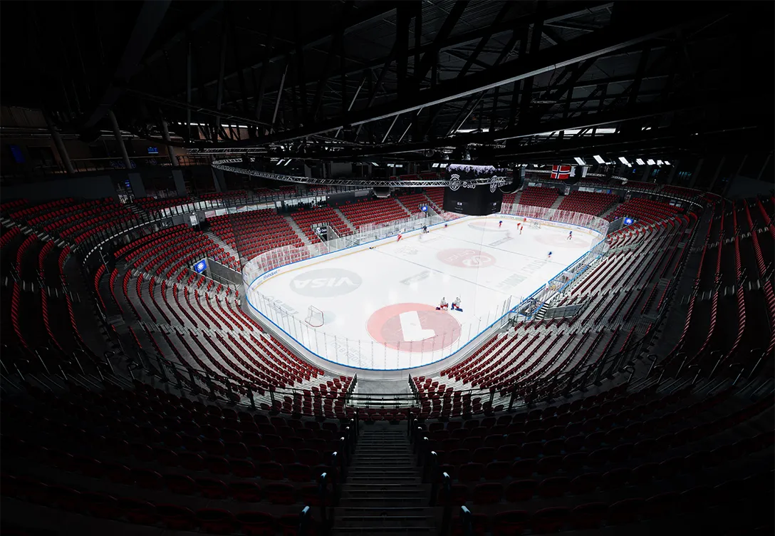 Empty ice hockey arena at Jordal Amfi stadium, with red seats and a rink ready for a game.