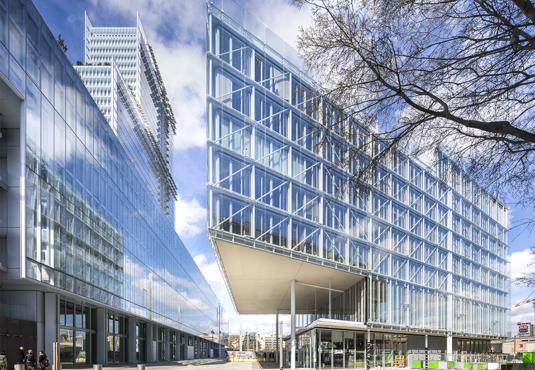 Maison de l'Ordre des Avocats, a modern glass building with sharp angles and reflective facades, set against a blue sky.