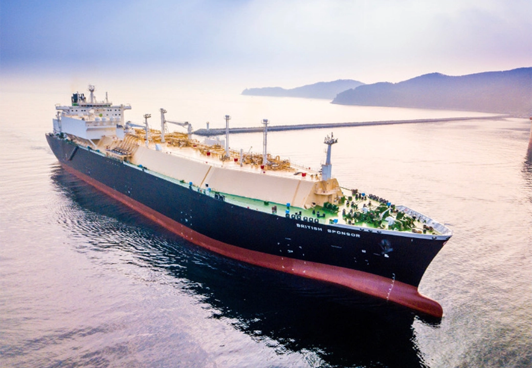 The LNG carrier from BP Shipping sails through calm waters with a hazy sky and distant coastline in the background.