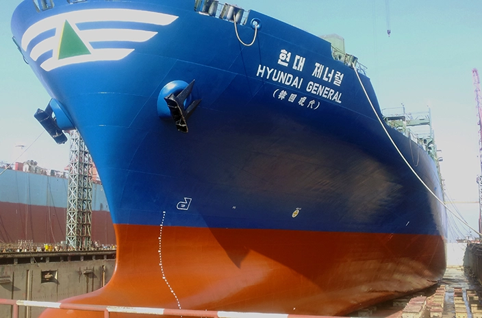 The "Hyundai General" container vessel is shown in a dry dock, featuring a blue and red hull with the ship's name and logo visible on the bow.