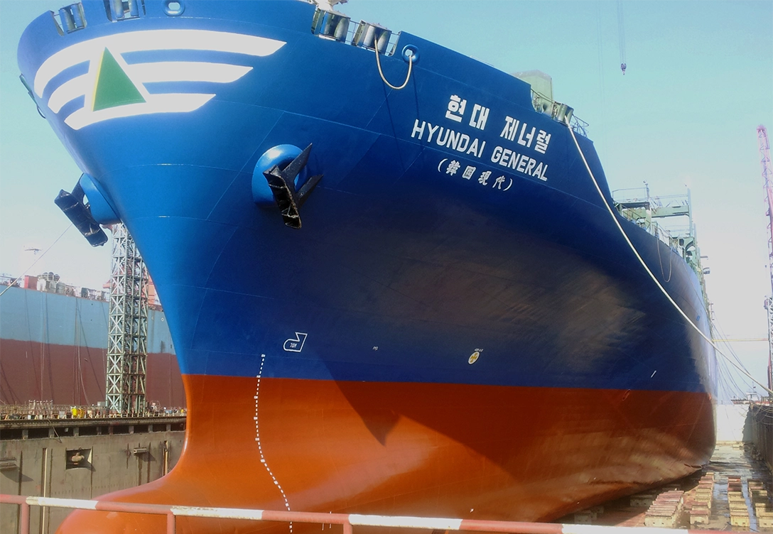 The "Hyundai General" container vessel is shown in a dry dock, featuring a blue and red hull with the ship's name and logo visible on the bow.