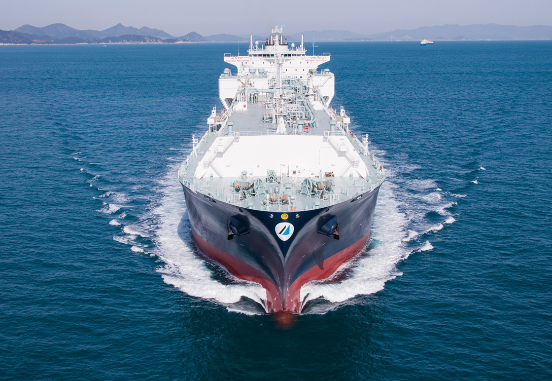 The Minerva LNG vessel is shown sailing through calm blue waters, with its white and grey superstructure and red hull.