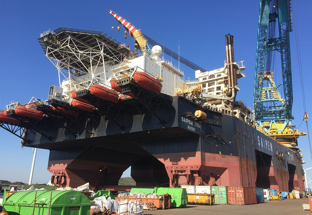 The Saipem 7000 semi-submersible crane vessel in a shipyard with its large cranes and lifeboats visible.