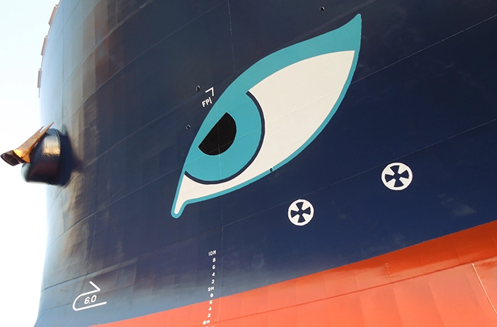 A close-up detail of a Neptune Lines vessel's hull shows a large painted eye design, with the anchor visible to the side and hull markings below.