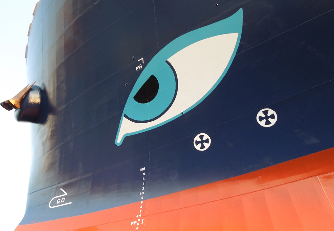 A close-up detail of a Neptune Lines vessel's hull shows a large painted eye design, with the anchor visible to the side and hull markings below.