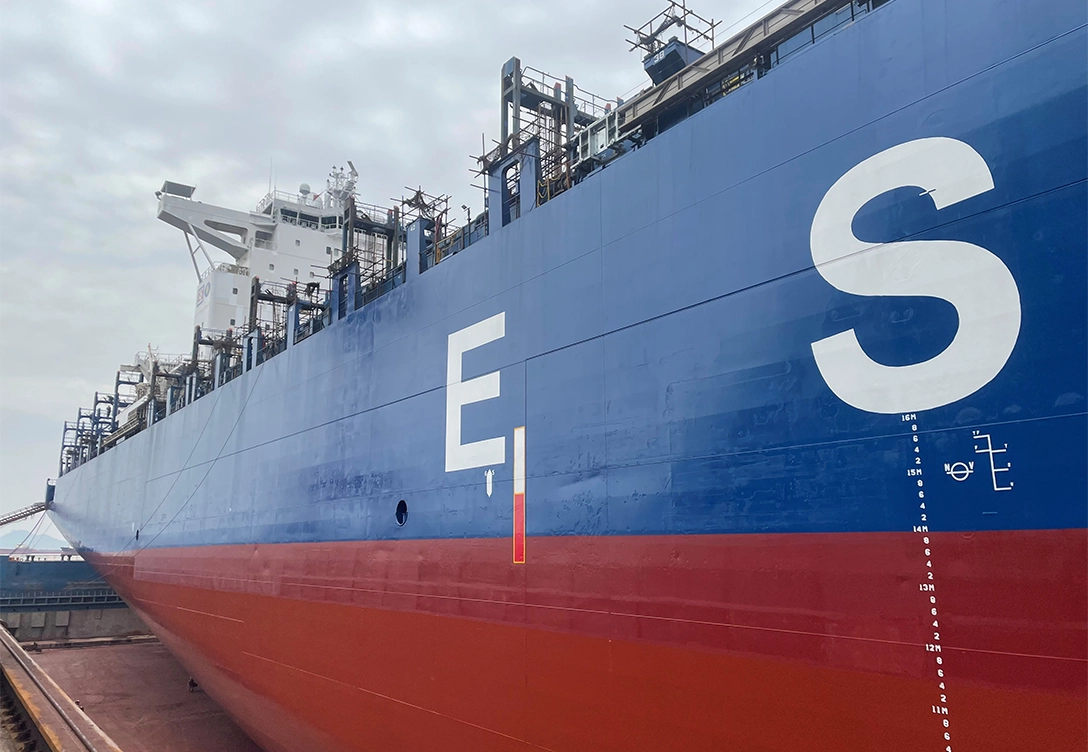 A close-up view of the side of the container vessel "ESL Dana," showing its blue and red hull with large white lettering.