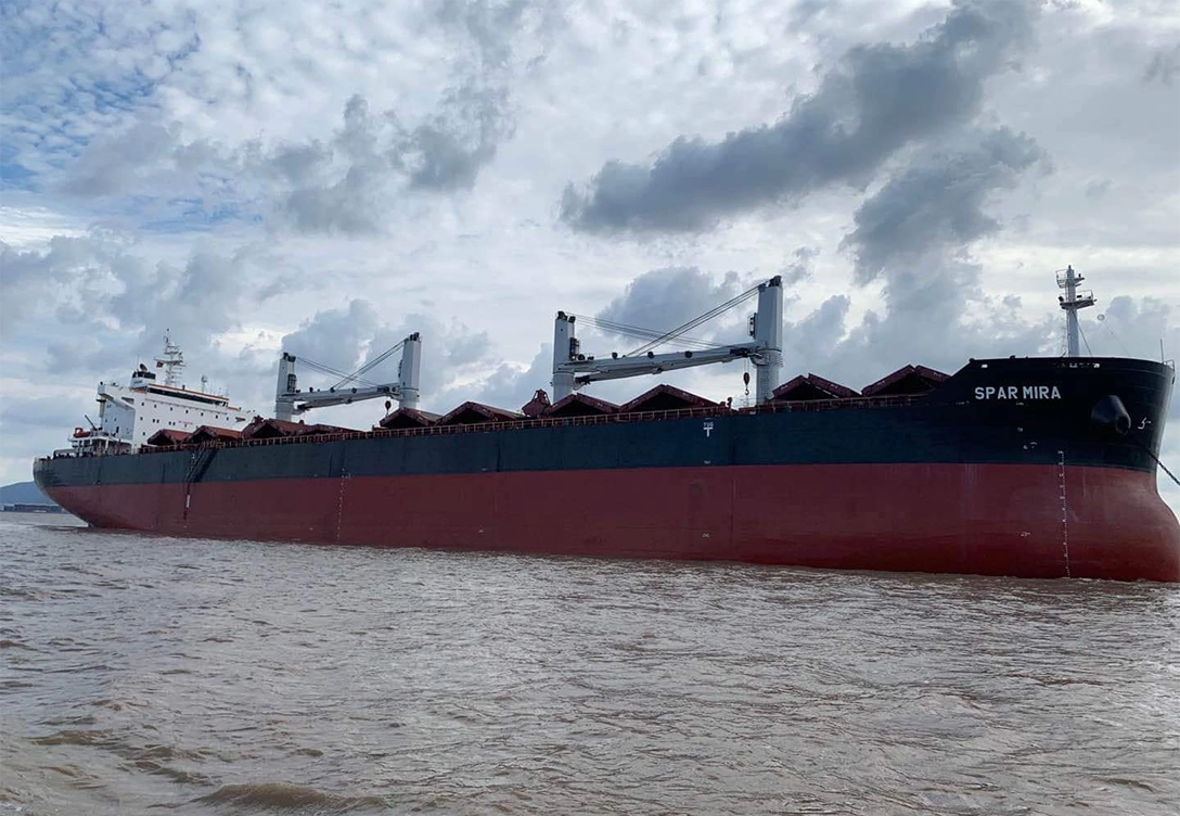 The vessel "Spar Mira" from Spar Shipping company sailing through cloudy weather, with its black and red hull visible above the waterline.