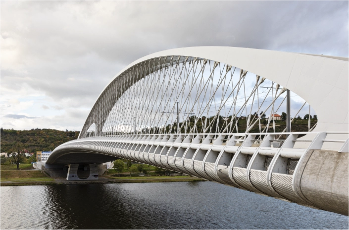A modern white arch bridge crossing a river, set against a cloudy sky.
