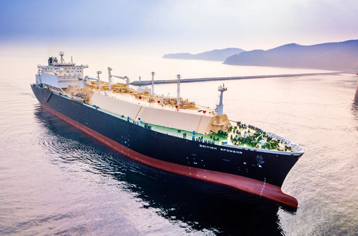 The LNG carrier from BP Shipping sails through calm waters with a hazy sky and distant coastline in the background.