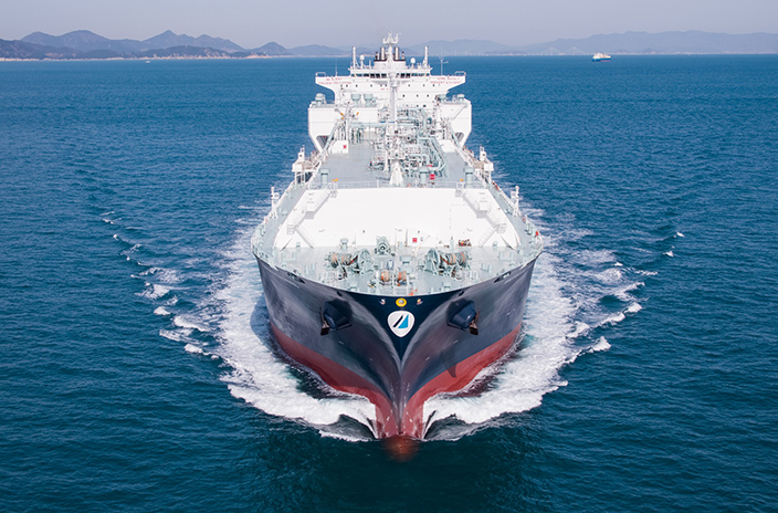 The Minerva LNG vessel is shown sailing through calm blue waters, with its white and grey superstructure and red hull.